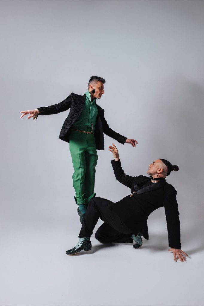 Two dancers mid-movement in black and green on a pale studio ground.